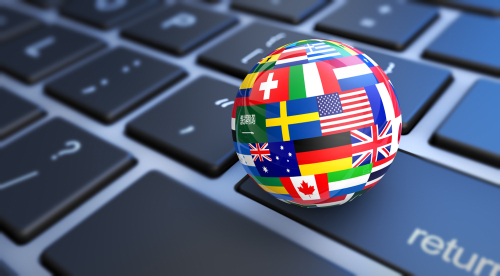 Picture of a keyboard that has a tiny ball sitting on it that has country flags all around the ball.